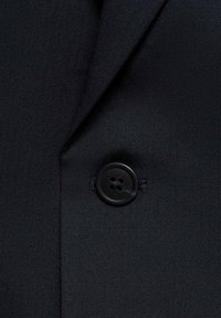 Țesătură de costum negru, personalizată, cu o textură netedă. Dispune de un buton rotund negru cu patru găuri, atașat la rever.