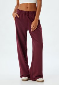 Bordeauxrode sweatpants met een relaxte pasvorm, een elastische tailleband en zijzakken. Gemaakt van zachte stof, met een eenvoudig ontwerp en duurzame textuur.