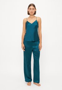 Teal sateng camisole med tynne stropper, kombinert med matchende sateng vidde bukser, med en jevn tekstur og en avslappet passform.