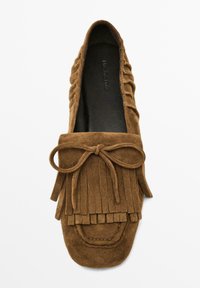 Brown suede moccasin with fringe detail, rounded toe, decorative bow on the vamp, and soft inner lining. Smooth texture throughout.