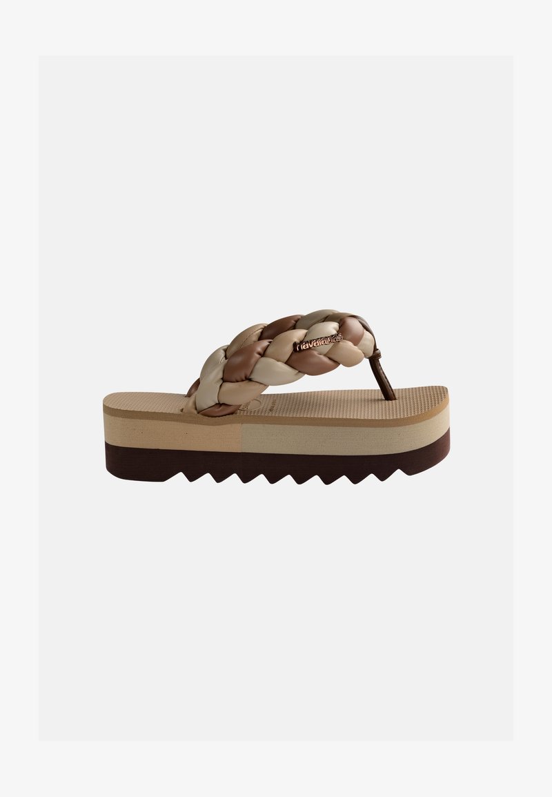 Παντόφλα σαγιονάρες με παχιά, ανάγλυφη σόλα και πλεγμένα μπεζ και καφέ λουριά με μικρή μεταλλική λεπτομέρεια λογοτύπου.