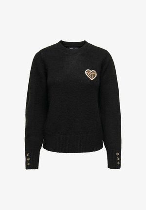Pull noir en tissu texturé, avec un patch en forme de cœur imprimé léopard sur le côté gauche de la poitrine et des accents de boutons au niveau des poignets.