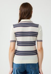 Strickpolo in cremiger Farbe mit horizontalen Streifen in Marineblau und Burgunder. Mit kurzen Ärmeln, einem Kragen und einem strukturierten Zickzackmuster.