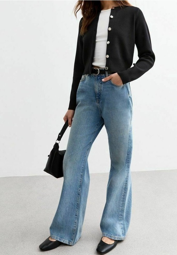 Černý pletený kardigán se stříbrnými knoflíky, kombinovaný se světlými modrými džínami s vysokým pasem a širokými nohavicemi, a černými plochými botami. Součástí je malá černá kabelka.