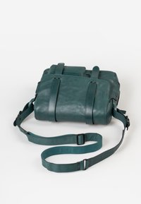 Teal leren tas met twee verstelbare banden, rechthoekige vorm, gladde textuur en subtiele hardware accenten. Minimalistisch ontwerp met functionele details.