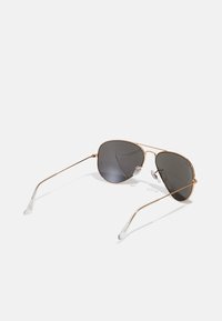 Ochelari de soare aviator din metal auriu, cu lentile gri, având pernuțe de nas din silicon transparent și brațe subțiri. Formă rotundă cu detalii minime.