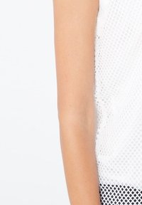 Top de malla blanco con un patrón texturizado, diseñado con una estructura de punto abierto. El dobladillo tiene un ligero borde desigual y sin terminar para añadir detalle.