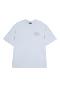 Camiseta oversized de color azul claro, hecha de algodón, con un pequeño logo impreso en burdeos en la zona del pecho izquierdo. Mangas cortas y cuello redondo.