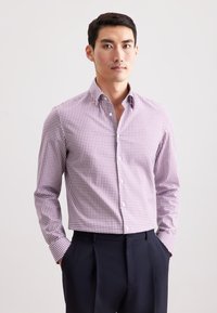 Rood en wit geruit overhemd met lange mouwen, hoge kraag en een getailleerd ontwerp, gecombineerd met donkere broeken. Gladde stofstructuur.