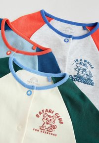 Three baby shirts with colorful raglan sleeves in red, blue, green, and beige. Screen prints feature a crocodile and a tiger.
