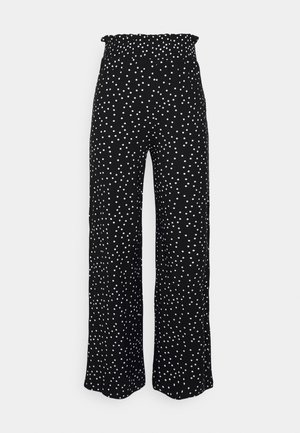 Pantalones negros de pierna ancha con cintura elástica y lunares blancos dispersos. La tela parece ligera con una textura suave.