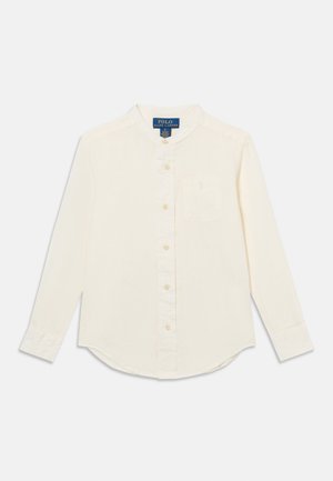 Kreemikas pikkade varrukatega nööpidega pluus mandariinkaelusega ja rinnataskuga, Polo Ralph Laureni silt kaeluse sees nähtav.