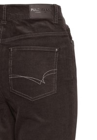Jean en velours côtelé marron foncé vu de dos avec une poche cousue et une étiquette de marque en cuir noir "PULZ JEANS" sur la ceinture.