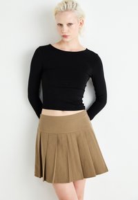 Un haut noir à manches longues et une mini jupe plissée marron. Le tissu est lisse, avec une coupe ajustée pour le haut et une structure évasée pour la jupe.