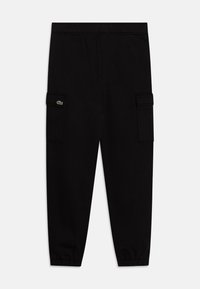 Pantalons de survêtement noirs en tissu doux avec une taille élastique, jambes fuselées et deux poches cargo latérales. Présente un petit patch logo.