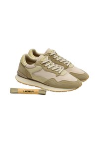 Paire de baskets en daim beige et marron clair avec des lacets blancs, accompagnée d'une paire supplémentaire de lacets beiges marqués "HOFF".
