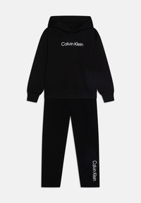 Čierna mikina s kapucňou a zodpovedajúce nohavice so bielym logom "Calvin Klein" na prednej strane a po ľavom stehne. Mäkký bavlnený materiál.