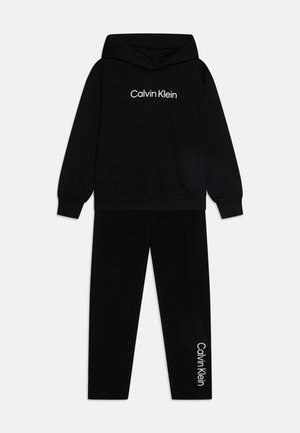 Musta kapuutsiga sviiter ja sobivad püksid, mille esiküljel ja vasakul jalal on valge "Calvin Klein" logo. Pehme puuvillane materjal.