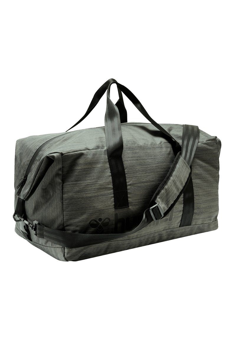 Grand sac de sport gris avec une texture lisse, deux poignées supérieures, une bandoulière réglable et un logo sur le côté. Dispose d'une fermeture zippée.
