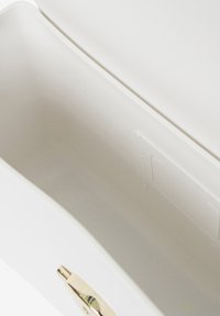 Interno della borsa bianca con una texture liscia e un accentuato hardware dorato. La forma è rettangolare con un design minimalista e senza motivi.