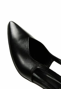 Chaussure en cuir noir à bout pointu avec un design à découpe sur le côté. Sa texture lisse et sa silhouette élégante mettent en valeur sa forme structurée.