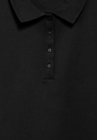 Svart polo tröja med strukturerad krage och fyra knappslå. Tyget är texturerat och ribbat, vilket ger ett solitt och enhetligt utseende.