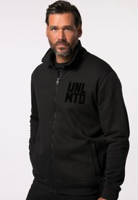 Sort lynlås sweatshirt med høj krave, der har et blankt "UNLMTD" logo på venstre bryst og sidelommer, lavet af struktureret stof.