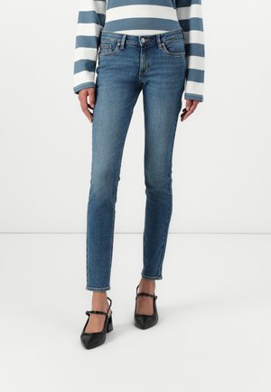Tunna blå denimjeans med en blekning i tvätterna, femficksdesign och midjehöjd, tillsammans med svarta spetsiga klackar.