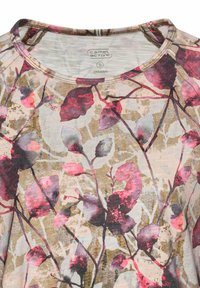 Bluse aus Bio-Baumwolle mit floralen Mustern, featuring einem Rundhalsausschnitt, rosaroten und lila Blättern auf einem hellbraunen Hintergrund und einer strukturierten Oberfläche.