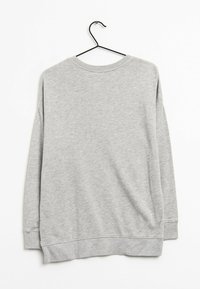 Felpa grigia con scollo rotondo, maniche lunghe e orlo a costine. Realizzata in tessuto morbido e testurizzato; appesa a un gancio di metallo nero.