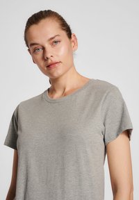 Grå kortærmet t-shirt lavet af blødt stof med rund halsudskæring. Fit er afslappet og fremhæver ærmerne og torsoen.