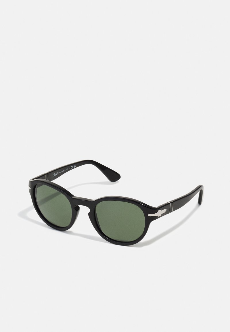 Black sunglasses with oval lenses featuring green tint. Made of smooth plastic, with silver accents on the temples.