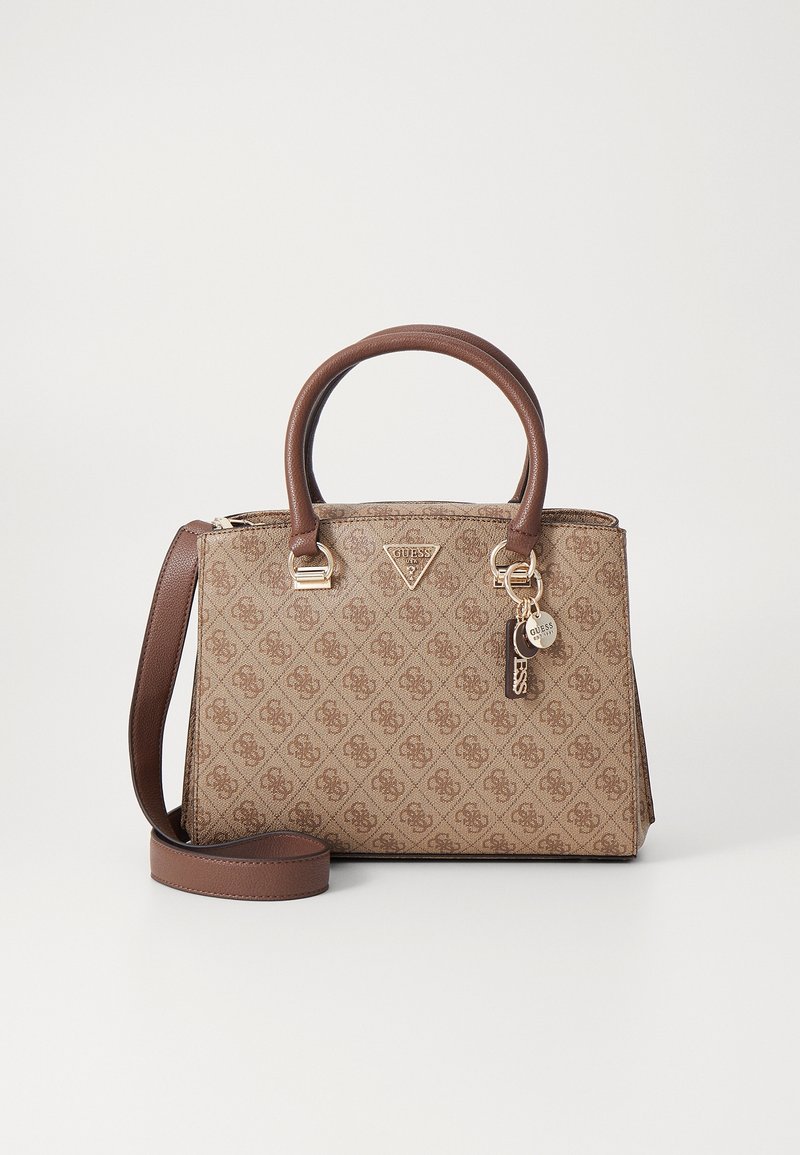 Sac à main Guess marron à motif, avec double poignée, bandoulière amovible et pendentif logo doré sur fond clair.