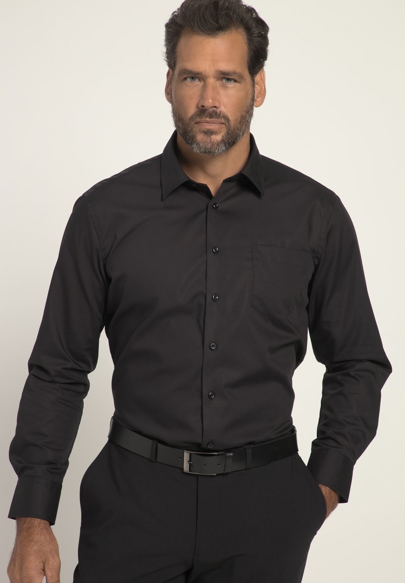 Schwarzes Langarmhemd mit Button-Down-Kragen und Brusttasche. Glatte Textur, taillierter Schnitt, kombiniert mit einem schwarzen Gürtel und Hosen.