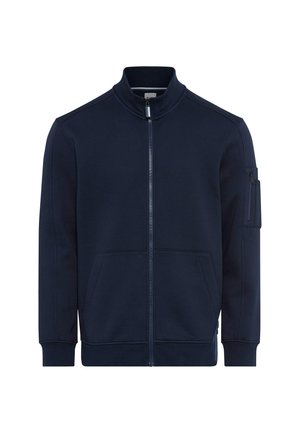 Marineblauwe ritstrui gemaakt van zachte stof, met een hoge kraag, twee voorzakken en een ritszak op de mouw.