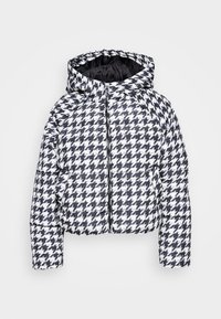 Svartvit houndstooth-mönstrad pufferjacka med huva och framdragkedja, visad mot en enkel vit bakgrund.
