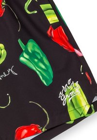 Zwarte stof met een patroon van rode en groene pepers, voorzien van gestileerde gebogen accenten en witte tekstdetails. Gladde textuur.