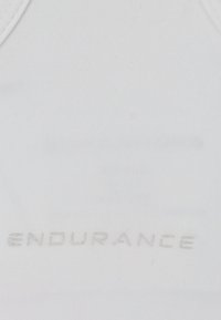 Valkoinen urheilu toppi, joka on valmistettu venyvästä kankaasta. Siinä on sileä pinta ja kohokuvioitu "ENDURANCE" logo edessä.