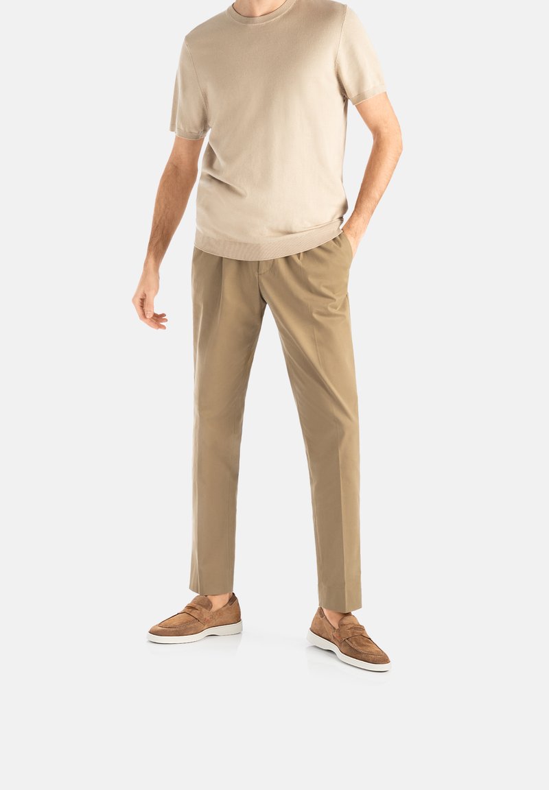Beige kortærmet crewneck t-shirt, khaki bukser og brune slip-on sko med hvide såler. Casual pasform, glat stof, minimalistisk design.