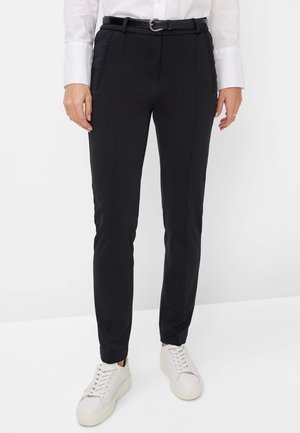 Black tailored pants made of stretch fabric, featuring side pockets, a slim fit, and a shiny black belt with a circular buckle. Worn with white sneakers.