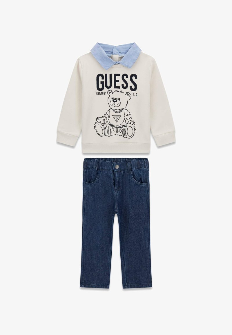 Sweat-shirt crème avec un col en denim et un motif d’ours ; assorti à un pantalon en denim bleu foncé avec poches avant et ceinture élastique.