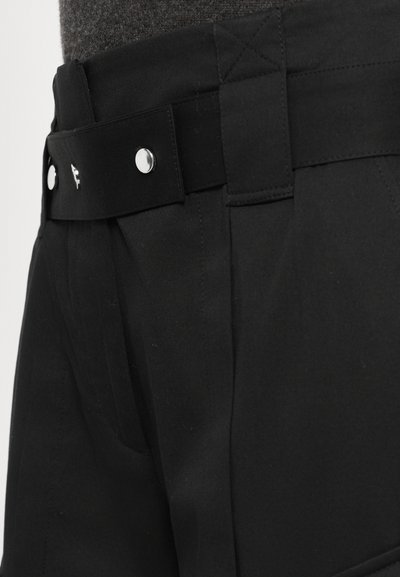 Black shorts with a flat waistband, featuring silver hardware and pleat details. Made from a smooth fabric with a matte finish.