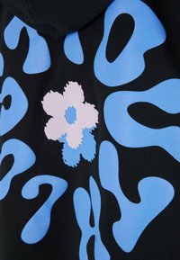 Tela negra con formas azules abstractas y un diseño de flor blanca y azul en el centro.