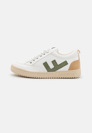 Baskets basses blanches avec semelle et talon beige, dotées d'un logo latéral vert et d'une fermeture à lacets.