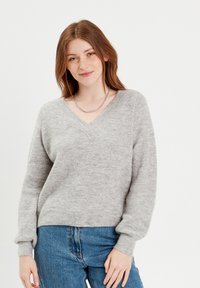 Grå, ribbet striktrøje med V-hals og lange ærmer, der har en løs pasform og blød tekstur. Sammen med blå denim jeans.