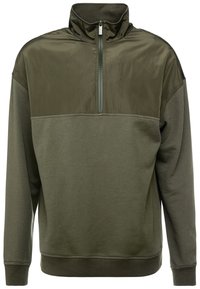 Felpa pullover verde oliva con colletto alto, zip frontale a metà e un mix di materiali lisci e testurizzati.
