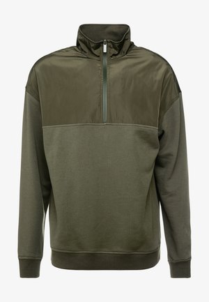 Olive roheline kapuutsiga sviiter, millel on kõrge krae, pooltõmbe lukk ja siledate ja tekstureeritud materjalide segu.