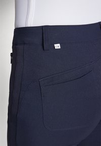 Pantalones de mezcla de algodón azul marino con una textura suave, que cuentan con un bolsillo trasero y una etiqueta de tela blanca con el logo "CK".