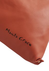 Pochette en cuir orange structuré avec une texture élégante et une inscription noire "Manila Grace" sur la surface. Contient un détail en métal doré.