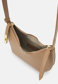 Borsa a mano in pelle marrone chiaro con una texture liscia, forma arrotondata, chiusura con zip dorata e tracolla regolabile. L'interno include una tasca con zip.